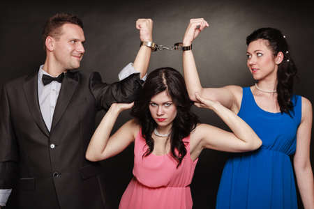 Marital infidelity concept. Love triangle two women one man passion of love hate. Mistress betrayal within the family. Black background.の写真素材