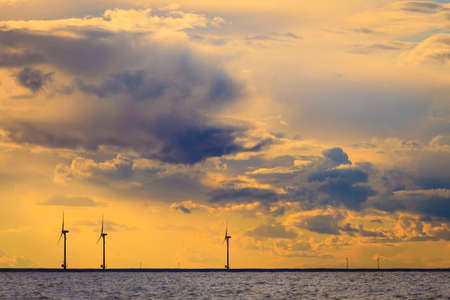 wind turbines power generator farm for renewable energy production along coast baltic sea near Denmark at sunset or sunrise. Alternative green energy ecology.の写真素材
