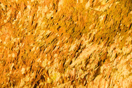 Background of natural wet orange stone wall texture rough rock surfaceの写真素材