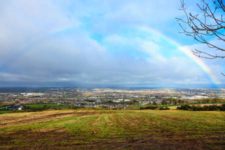 View of town Cork, County Cork, Ireland Europe. Cloudscape with colorful rainbow over autumn city, beautiful colors phenomenon in blue sky, overcast weather, nature landscapeの写真素材