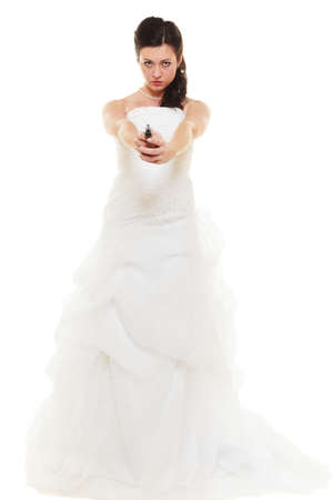 Wedding Day. Angry betrayed bride concept. Woman in white dress with gun isolated on white. Studio shot.の写真素材