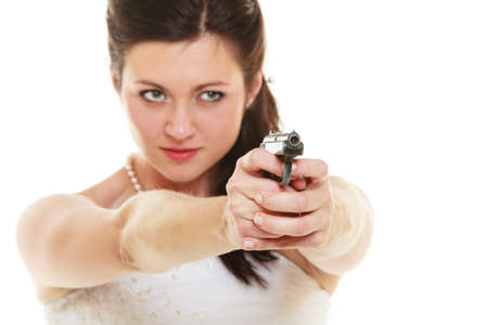 Wedding Day. Angry betrayed bride concept. Woman in white dress with gun isolated on white. Studio shot.の写真素材