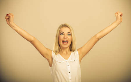 Blonde girl spreading hands with joy, happy successful young woman with arms up. Success positive emotions.の写真素材