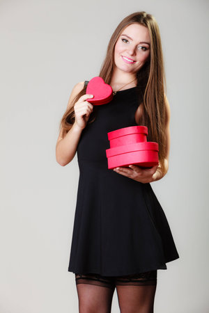 Happiness, valentines day and love concept. Lovely elegant woman in black dress with red...