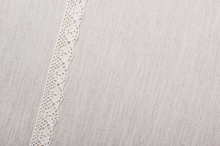 Lace ribbon on natural linen, bright cloth fabric background. Border frameの写真素材