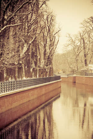 Winter season and seasonal specific. Park with river and embankment covered with snowの写真素材