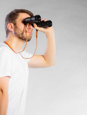 Young handsome man lifeguard on duty or tourist looking through binocular studio shot on grayの写真素材