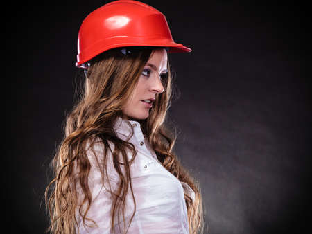 Woman in male specialities. Girl in red helmet. Safe by work concept. Sexy young feminist on black grey background.の写真素材