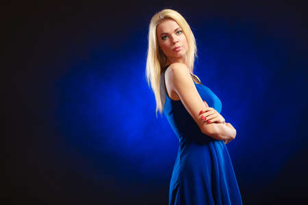Party, new year, celebration, disco concept - Portrait attractive fashion woman, blonde long hair girl in evening dress night club dark blue backgroundの写真素材