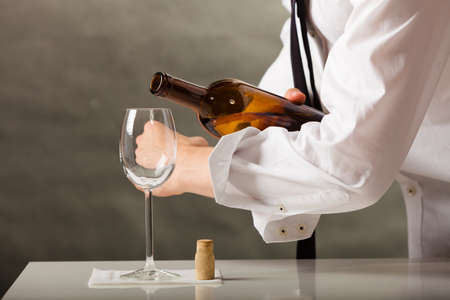 Male waiter or butler serving pouring wine into glass.の写真素材
