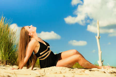 Summer vacation day freetime concept. Sitting woman body sunbathing delight on beach seaside.の写真素材