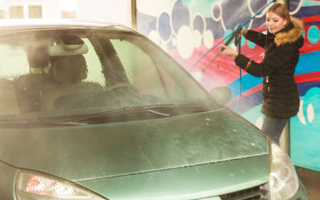 Auto wash. Young attractive blonde woman washing the dirty car on open airの写真素材