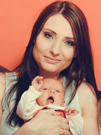 Parenting and love concept. Closeup one month old baby girl in the comfort of moms arms, portrait