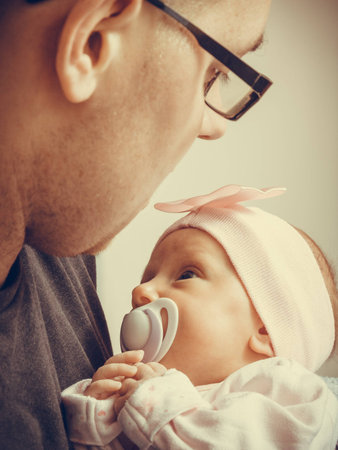 Parenting concept. Father holding delicate his newborn baby girl, at homeの写真素材