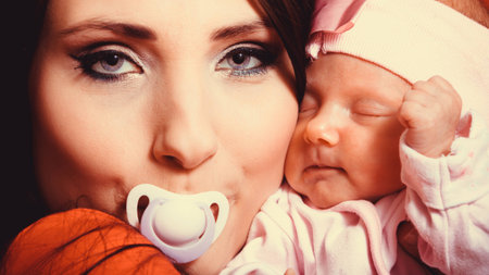 Parenting and love concept. Closeup funny mother with nipple in her mouth hugging one month old baby...