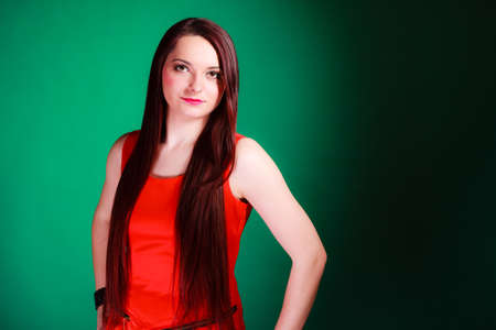 Party, celebration and date concept. Attractive young log hair woman in red dress on green background. Studio shot.の写真素材