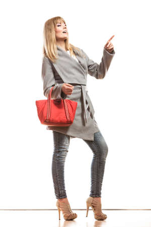 Fashion and advertisement concep t.Full body woman elegant gray belt coat holding red handbag pointing copy space empty blank isolatedの写真素材