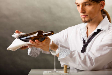 Male waiter or butler serving pouring wine into glass.の写真素材