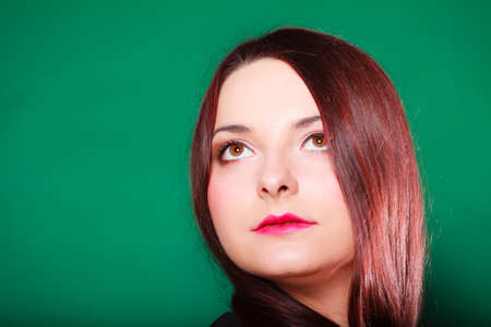 Hair care, hairdresser and hair stylist. Thoughtful red haired woman with classical coiffure looking upwards on green background. Studio shot.の写真素材