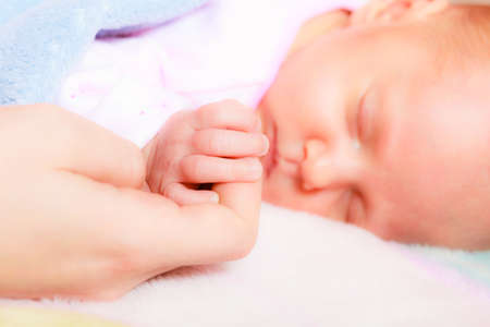 parenting and love concept. Closeup tiny hand the sleeping baby girl in the palm of motherの写真素材