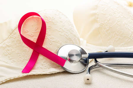 Healthcare, medicine and breast cancer awareness concept. Closeup pink ribbon and stethoscope on female bra.の写真素材