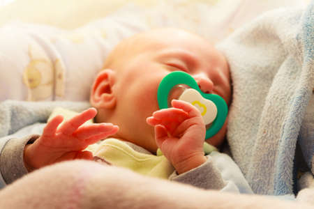 Closeup little newborn baby girl 24 days sleeping with dummy in mouthの写真素材