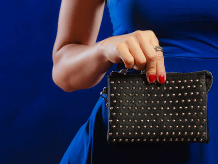Fashion elegant evening outfit. Close up female hand holding black rivet leather handbag bagの写真素材