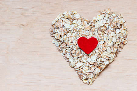 Dieting healthcare concept. Oat cereal heart shaped on wooden surface. Healthy food for lowering cholesterol, protect heart.の写真素材