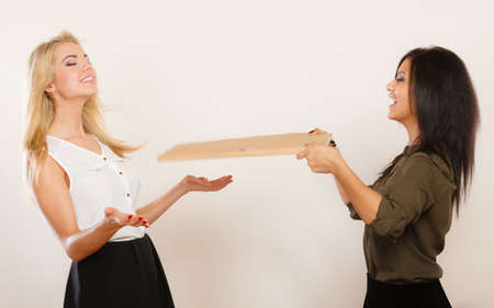 Beautiful different race women friends black and white girls having fun blowing wind with board studio shotの写真素材