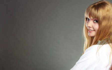 Face of young blonde woman with bangs gray background copy space text area