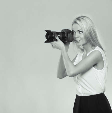 Photographer girl shooting images. Attractive blonde woman taking photos with camera. Black and white photoの写真素材