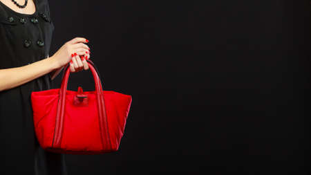 Fashion beauty and elegance concept. Elegant lady holding red handbag in hand on black background copy space text areaの写真素材