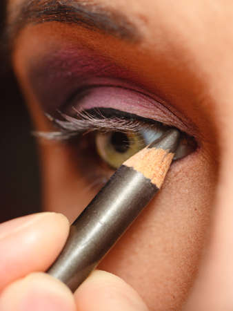 Cosmetic beauty procedures and makeover concept. Closeup part of woman face eye makeup detail. Using color pencilの写真素材