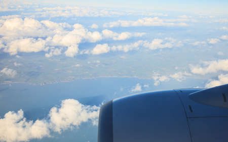 Blue white cloudy sky and engine. View from window of airplane flying in clouds. Skyscape cloudscape. Bird's eye.の写真素材