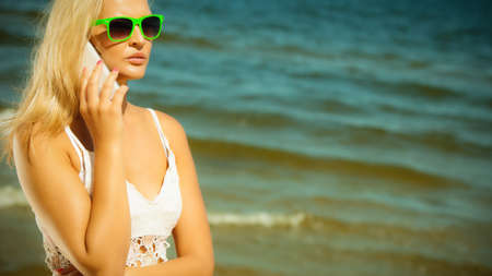 Technology and communication. Young woman pretty girl talking on mobile cell phone using smartphone on beachの写真素材