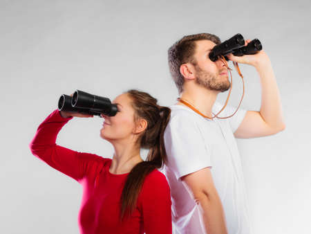 Young man and woman lifeguards on duty or tourist couple looking through binocular studio shot on grayの写真素材