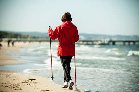 Nordic walking. Woman hiking on the beach. Active and healthy lifestyle.