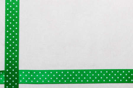 Festive celebration party frame. Polka dot green blue satin ribbon on white cloth backgroundの写真素材