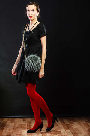 Elegant fashion outfit. Fashionable woman legs in red vivid color pantyhose black shoes and gray handbagの写真素材