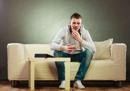 Modern technologies connection leisure concept. Young handsome man relaxing on couch with headphones...