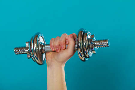 Bodybuilding. fit man exercising with dumbbells. Closeup young guy lifting weights on blueの写真素材