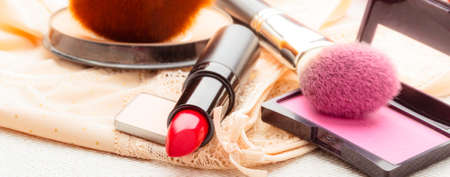 Women beauty concept. Makeup supplies various cosmetics. Red lipstick, poudre and rouse cheeks on lace langerie.の写真素材
