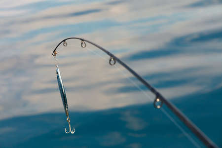 Sport and recreation. Fishing bait - rod with wobbler against the blue sea water surfaceの写真素材