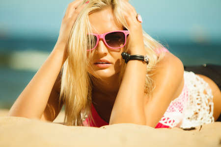 Holidays, vacation and summer fashion concept. closeup attractive blonde girl in pink sunglasses on beach outdoorの写真素材