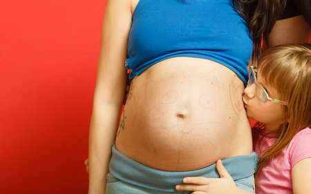 Pregnancy, motherhood and happiness concept. pregnant woman with painted cat face on the belly and...