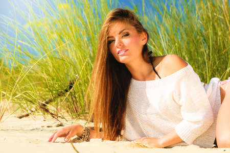 Young woman female model posing outdoor on background of dunes sky and grassの写真素材