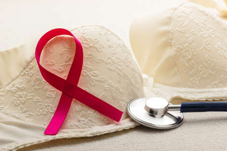 Healthcare, medicine and breast cancer awareness concept. Closeup pink ribbon and stethoscope on female bra.の写真素材