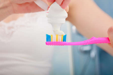 Dental health care. Closeup woman hands is holding toothbrush and placing toothpaste on it.の写真素材