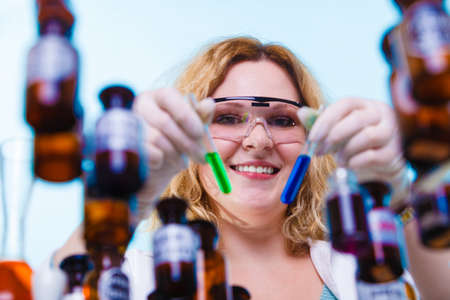 Experiment, research in progress. Chemist woman or student girl, laboratory assistant or scientific researcher with chemical glassware test flask on blueの写真素材