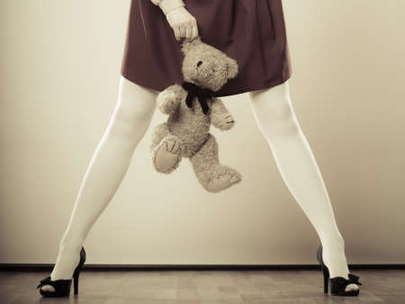 Mental disorder concept. Young childlike woman wearing like puppet doll holding teddy bear toy studio shotの写真素材